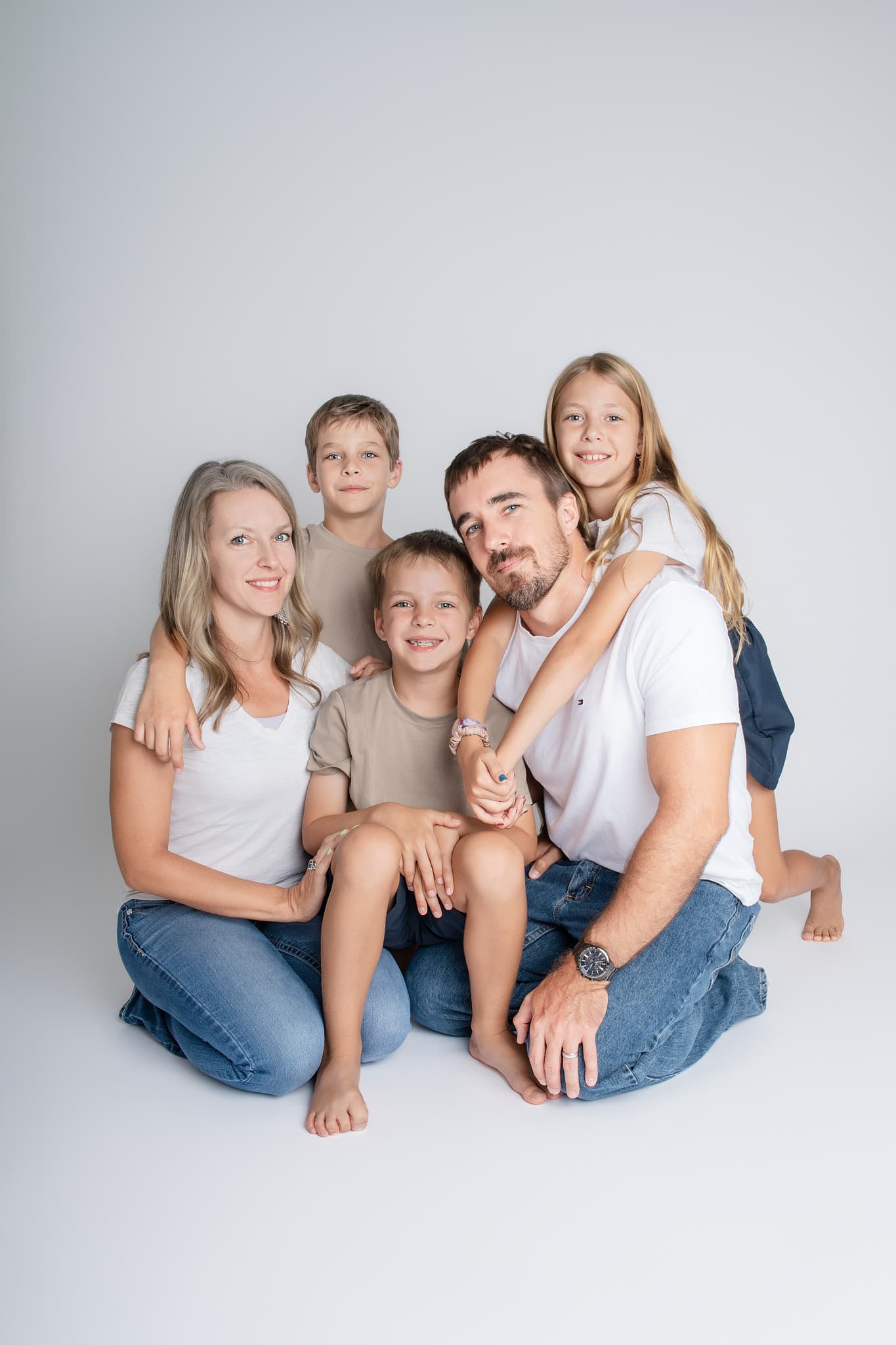 A family of five sitting together on the floor of the Brandon studio, three children between their parents